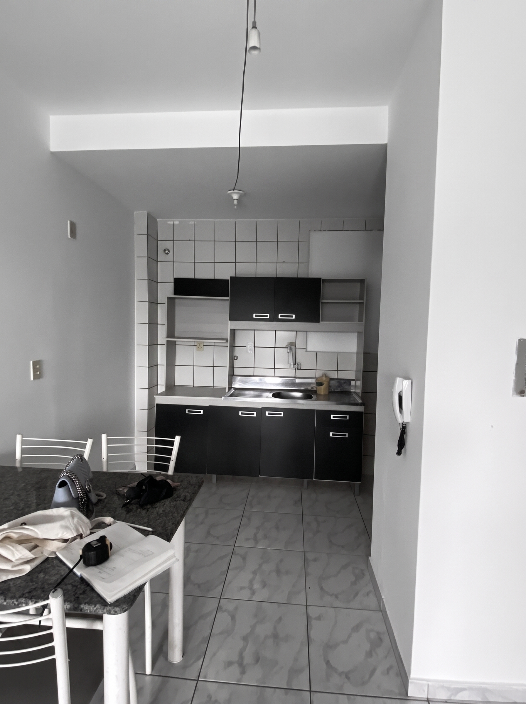 Cozinha antes da transformação, com revestimento claro, armários pretos e mesa de jantar