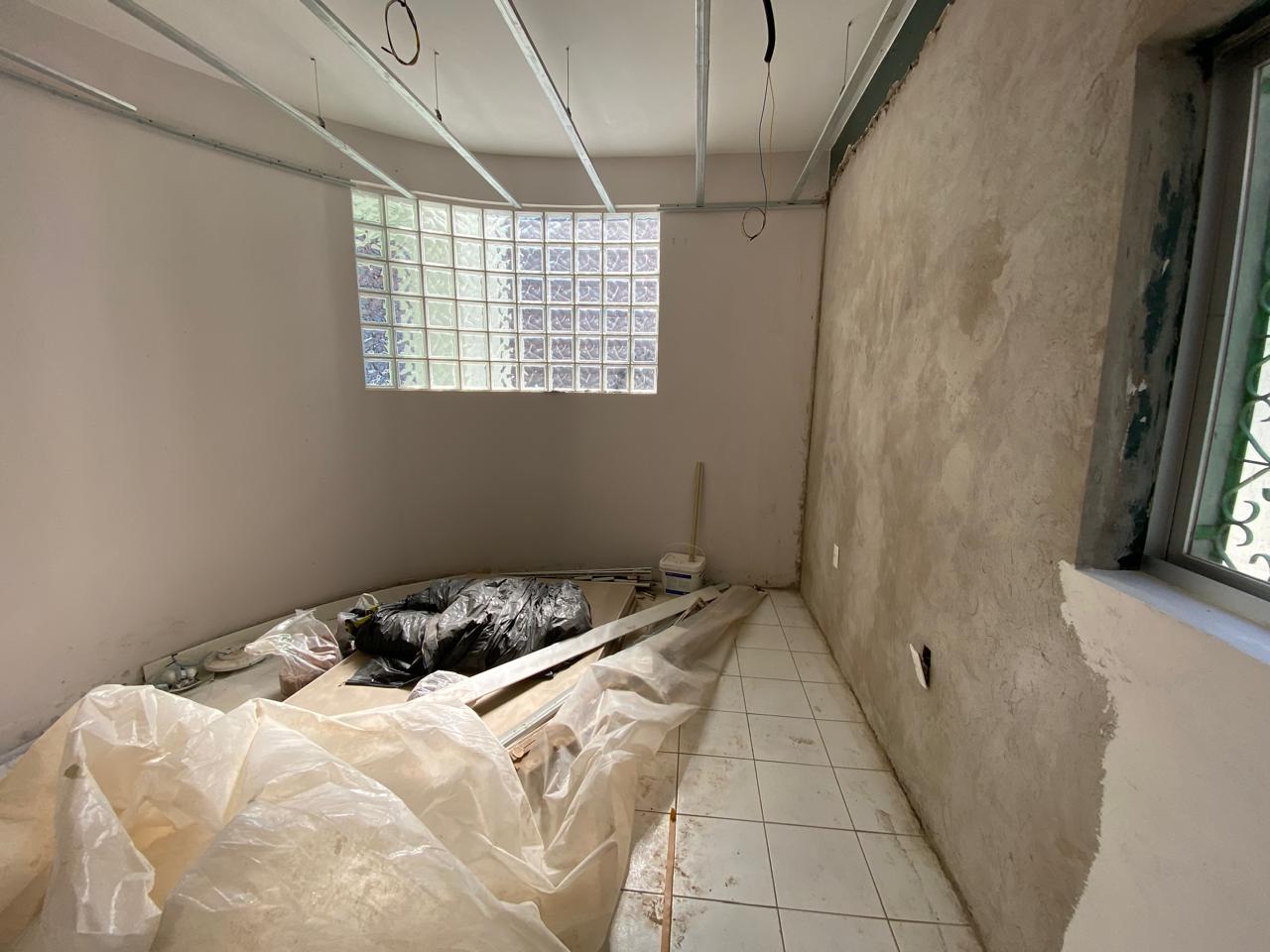 Ambiente antes da transformação, em obra, com janela de blocos de vidro e materiais no piso