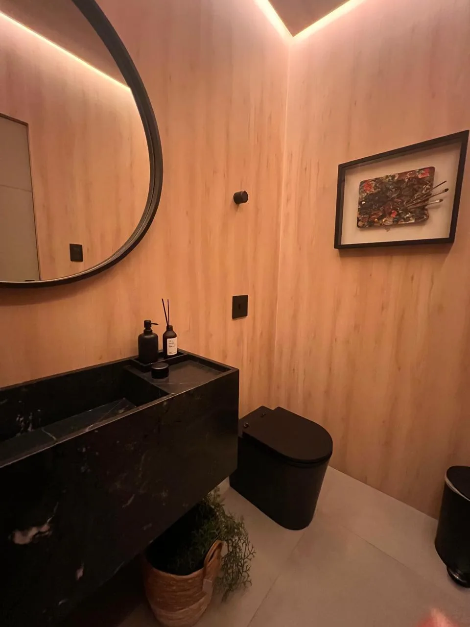 Lavabo depois da transformação, com painel amadeirado, iluminação indireta e espelho redondo